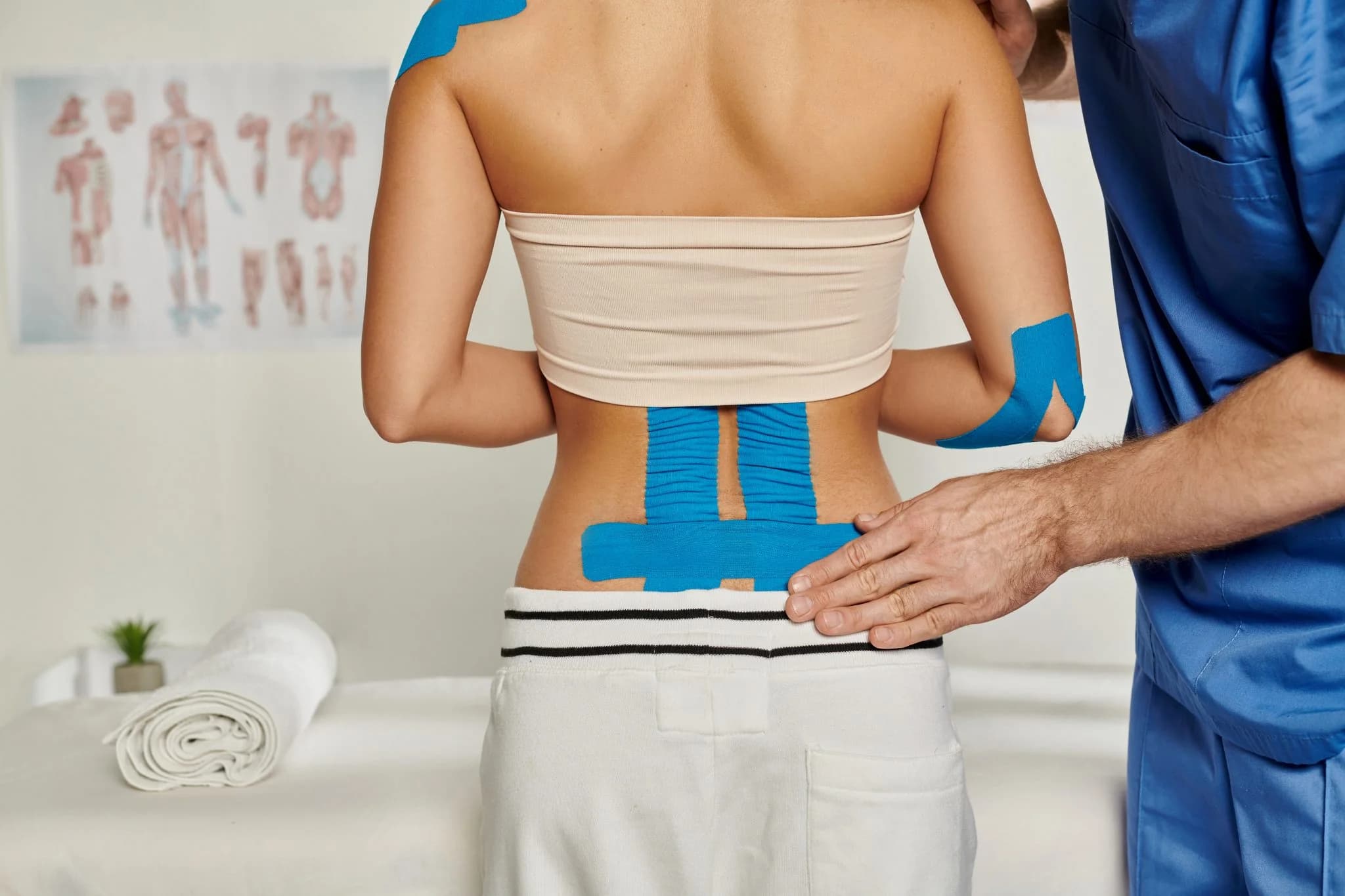 Kinesiology tape applied along a patient's lower back and shoulder
